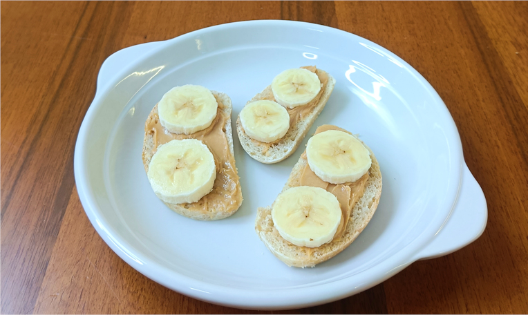 merenda sana per la scuola fette di pane con splamato burro di arachidi e sopra fettine di banana su di un piatto bianco