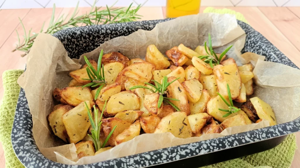 patate al forno senza bollitura, teglia di patate decorata con rametti di rosmarino
