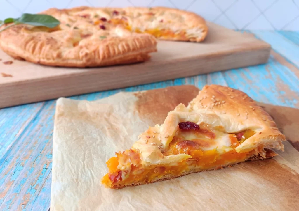torta salata zucca scamorza e speck, fetta appoggiata sulla carta da forno